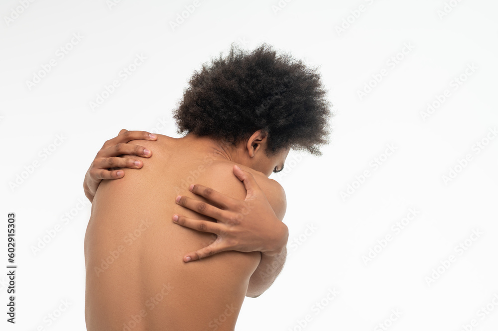 Curly-haired african american guy suffering from pain in his back Curly-haired african american guy suffering from pain in his back