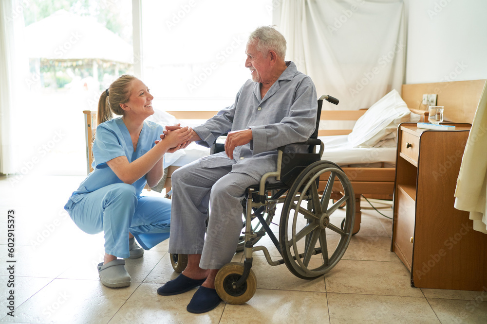 Nurse holding hand of elderly man in wheelchair at rehab center