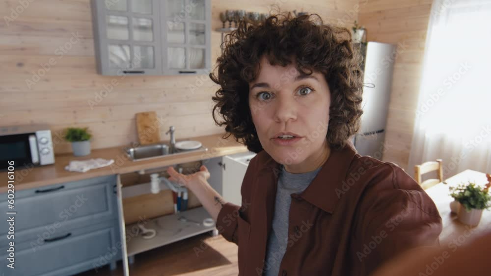 Handheld shot of mature Caucasian woman speaking about plumbing problem during video call with husband or repairman Handheld shot of mature Caucasian woman speaking about plumbing problem during video call with husband or repairman