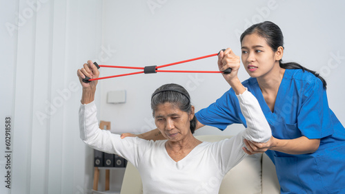 Concept of World Confederation for Physical Therapy. young physiotherapist caregiver helping mature elderly woman training with elastics in rehabilitation center  muscle weakness