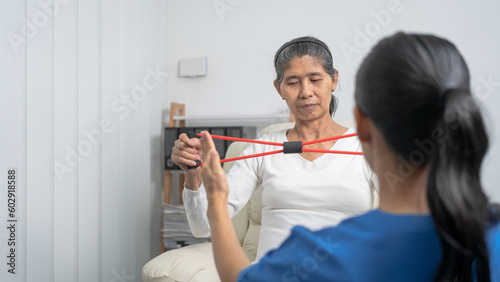 Concept of World Confederation for Physical Therapy. young physiotherapist caregiver helping mature elderly woman training with elastics in rehabilitation center, muscle weakness