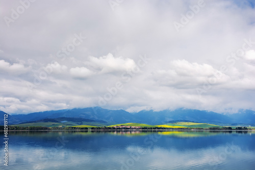 lake near the liptovsky mikulas, slovakia. liptovska mara water reserve in front of tatra mountains in spring. beautiful landscape on a cloudy afternoon photo