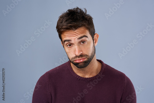 Bored, portrait and annoyed man in studio tired and moody against a grey background space. Fatigue, face and man with negative attitude posing with exhasuted expression while standing isolated photo