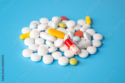 Pile, heap of different pills on blue background, concept medical picture