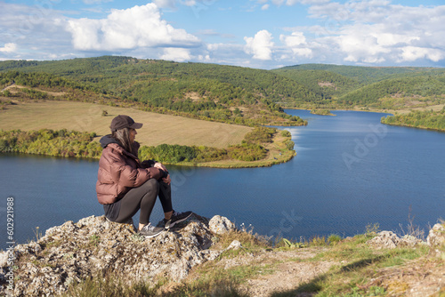 Traveler woman walking above a blue lake with stunning panoramic view .Traveling in the nature in Bulgaria . Pchelina Lake photo