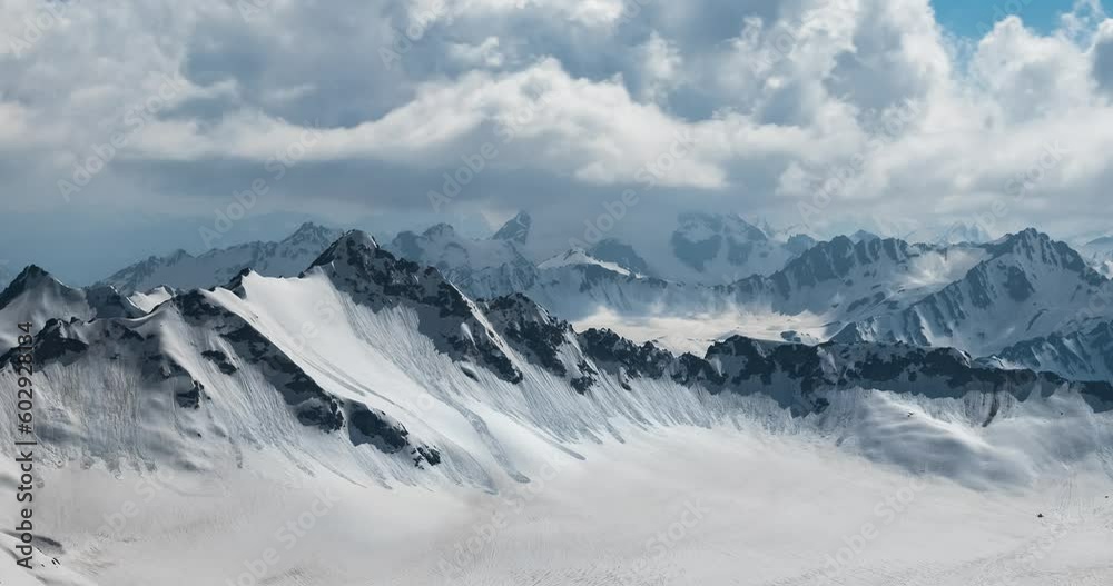 Air flight through mountain clouds over beautiful snow-capped peaks of mountains and glaciers. Air flight through mountain clouds over beautiful snow-capped peaks of mountains and glaciers.