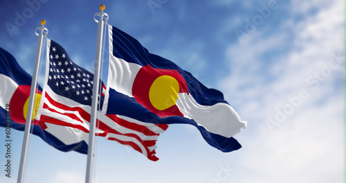 The Colorado state flag waving with the national flag of the US on a clear day