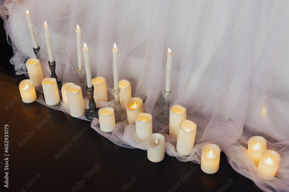 A different candles with a white curtain behind them for decoration at holidays.
