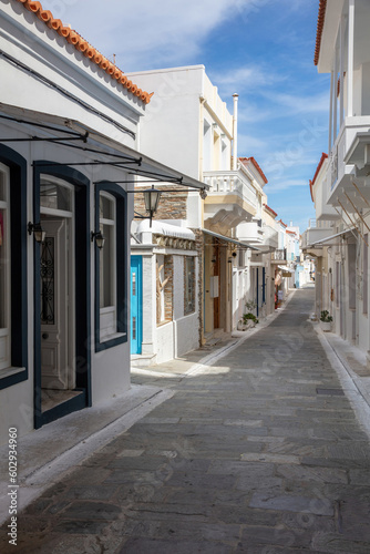Greece, Cyclades. Andros island, Chora town. Empty alley white wall blue sky background. Vertical © Rawf8