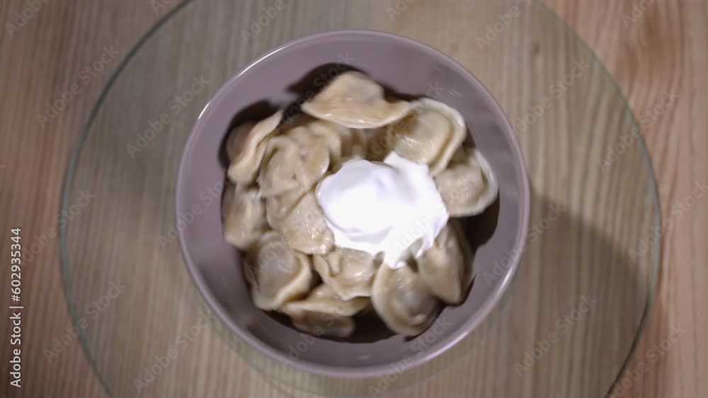 Female hand in glove spinning bowl with delicious dumplings in slow motion on tray. Unrecognizable cook bragging tasty dinner in cafe indoors Female hand in glove spinning bowl with delicious dumplings in slow motion on tray. Unrecognizable cook bragging tasty dinner in cafe indoors