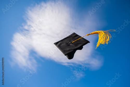 Obraz na plátně Graduation cap flies against the blue sky.