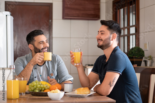 brazilian gay couple smiling and having breakfast at table