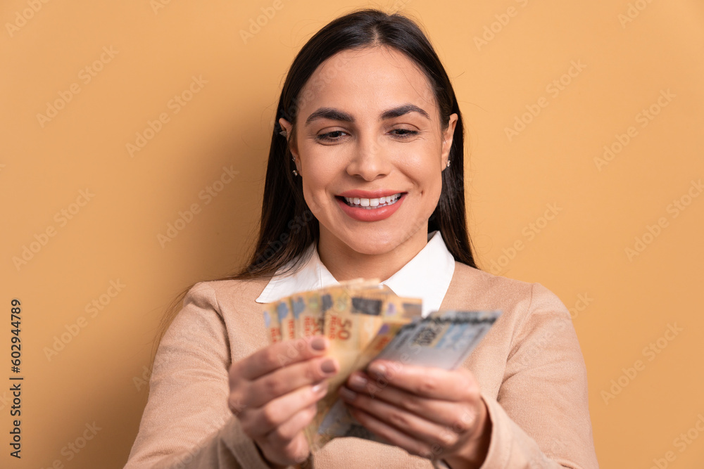 happy brazilian woman looking at brazilian money cash in beige colors. financial, credit, purchase, rich concept. happy brazilian woman looking at brazilian money cash in beige colors. financial, credit, purchase, rich concept.