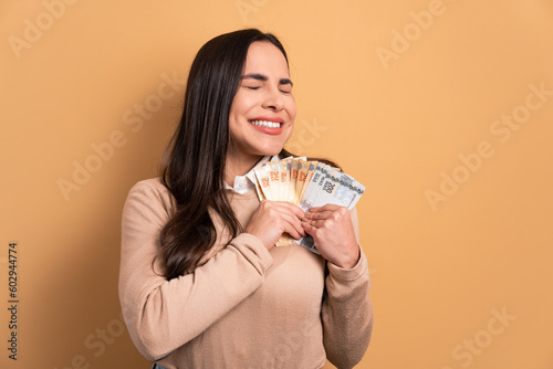 fun brunette young woman celebrating successful business money in all beige colors. business, loan, pay, wealth concept. 