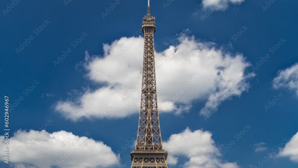 Eiffel Tower on Champs de Mars in Paris timelapse hyperlapse, France. Blue cloudy sky at summer day with green lawn and people walking around and relax