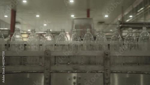 Conveyor belt showing clear plastic bottles moving along assembly line in manufacturing plant photo