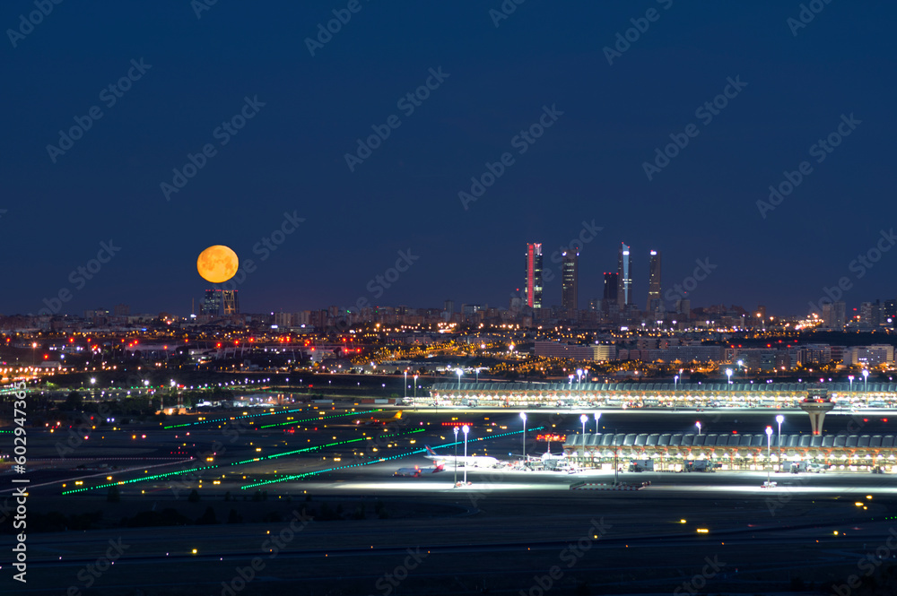 skyline de madrid con el aeropuerto aviones de noche y con la luna - obrazy, fototapety, plakaty 