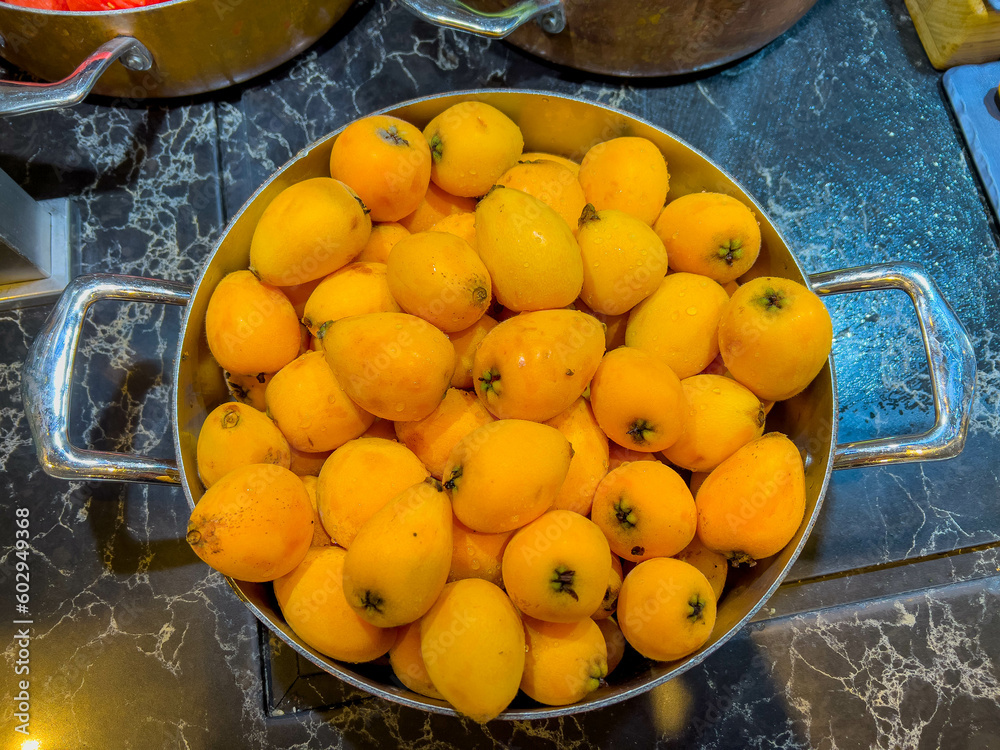loquat in iron saucepan at catering event on some festive event, restaurant, party or wedding reception. fruit. excellent source of calcium, magnesium, iron and especially potassium and vitamin C.