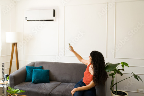 Fotografia Happy woman at home turning on the air conditioner