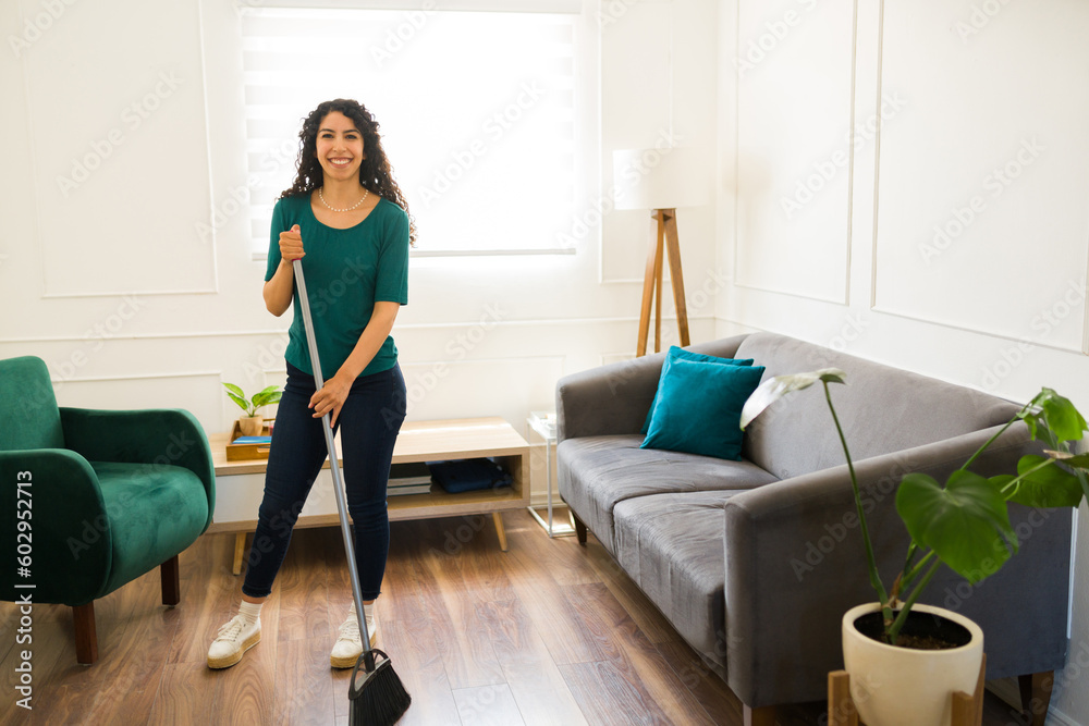 Fototapeta premium Cheerful woman sweeping the floor and smiling
