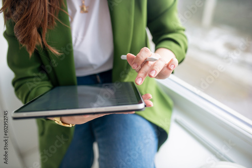 A girl in a green jacket works with a tablet