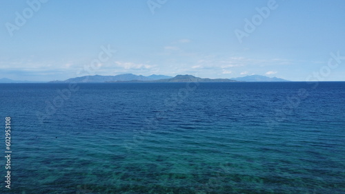 Seascape. Aerial view of the blue sea  white clouds and a tropical island on the horizon.