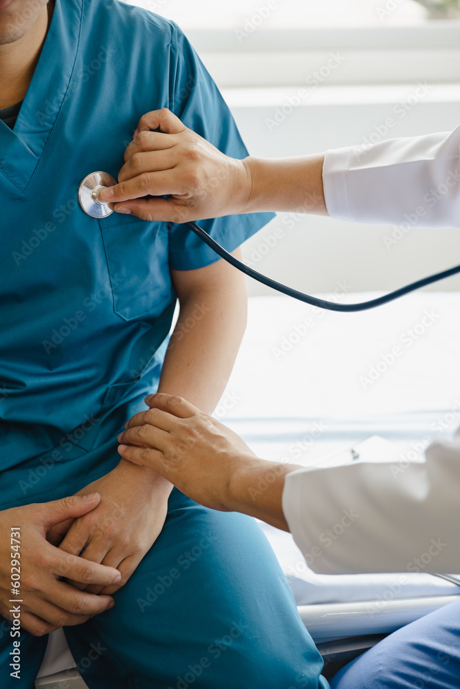 Closeup of male doctor using stethoscope making heart beat with patient in examining room at hospital. Medical checkup. Medical and healthcare.