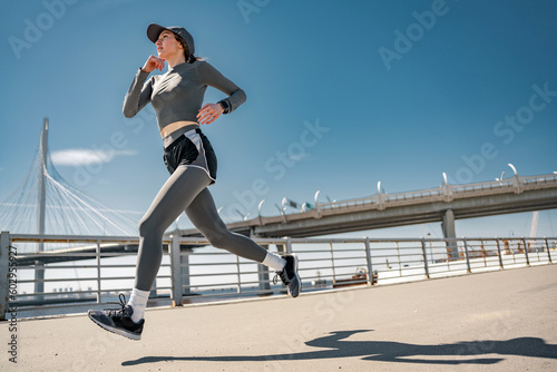 Spectacular foreshortening of a woman running fast in sportswear, cardio training. photo