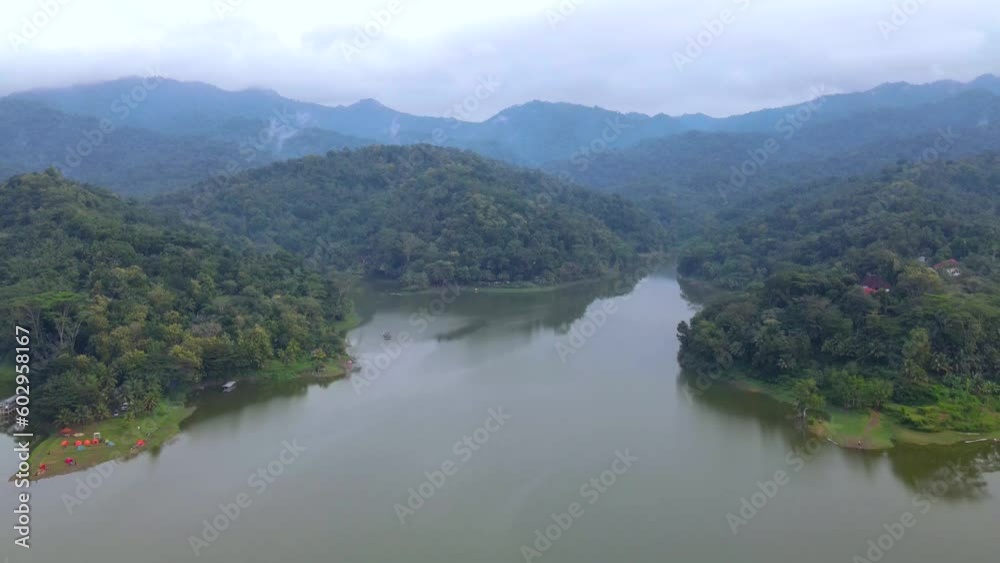 Aerial drone shot beautiful landscape of lake and forest in foggy morning. Forest woods and calm tranquil lake. Lake in the middle of forest. 4K aerial drone shot of Sermo Dam, Yogyakarta, Indonesia Aerial drone shot beautiful landscape of lake and forest in foggy morning. Forest woods and calm tranquil lake. Lake in the middle of forest. 4K aerial drone shot of Sermo Dam, Yogyakarta, Indonesia