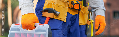 Photos Male builder wearing tool belt carrying toolbox at construction site