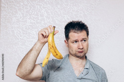 guy in a gray t-shirt holds a missing banana in his hand. Erection problem, male health