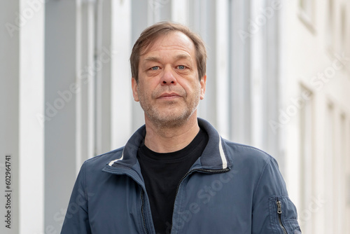 Street portrait of a man 40-50 years old on a neutral blurred urban background. Perhaps he is a buyer, an actor or a driver, a loader or a military pensioner, a passerby.