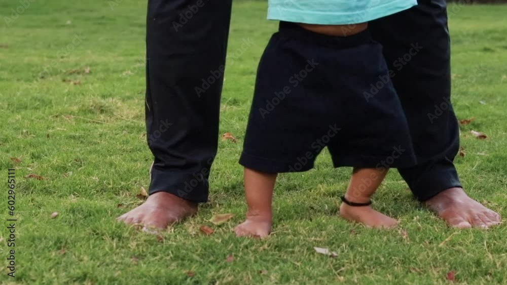 father helping son for walk at green grass at garden at evening father helping son for walk at green grass at garden at evening