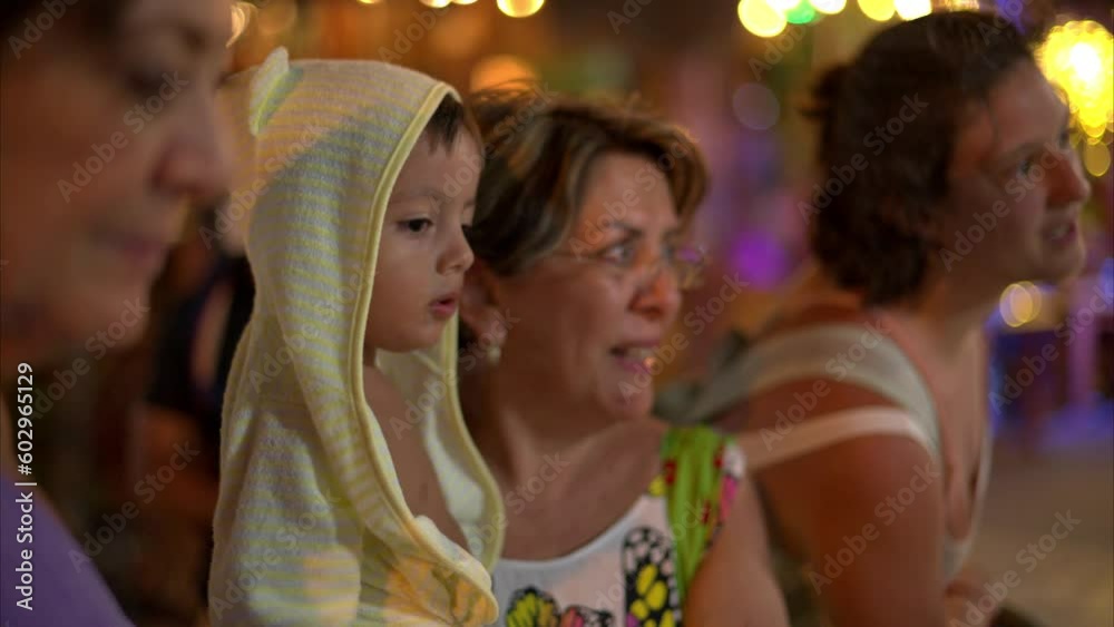 Latin hispanic baby boy toddler wearing a yellow bathrobe hoodie watching carefully while his grandmother carries him in isla mujers Mexico Latin hispanic baby boy toddler wearing a yellow bathrobe hoodie watching carefully while his grandmother carries him in isla mujers Mexico
