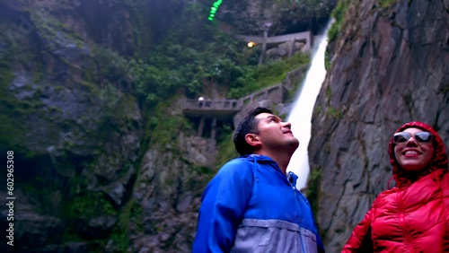 Young hispanic couple look around under waterfall at Baños, Ecuador