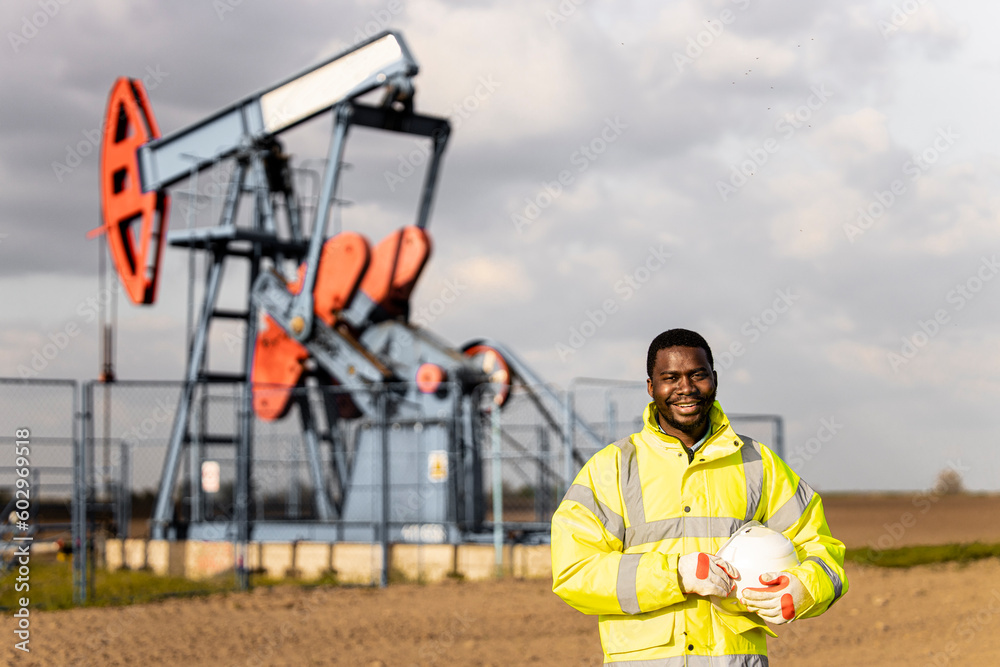 Portrait of an oil field worker standing in front of the oil rig. Portrait of an oil field worker standing in front of the oil rig.