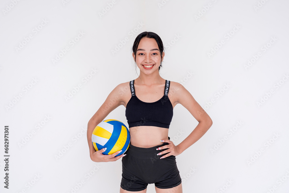 A sporty and athletic young woman posing while holding a volley ball on one hand. Isolated on a white background. A sporty and athletic young woman posing while holding a volley ball on one hand. Isolated on a white background.