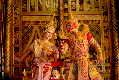 Beautiful Asian woman wear Thai traditional dress action of dancing together with Thai classic masked from the Ramakien character as red giant in room.