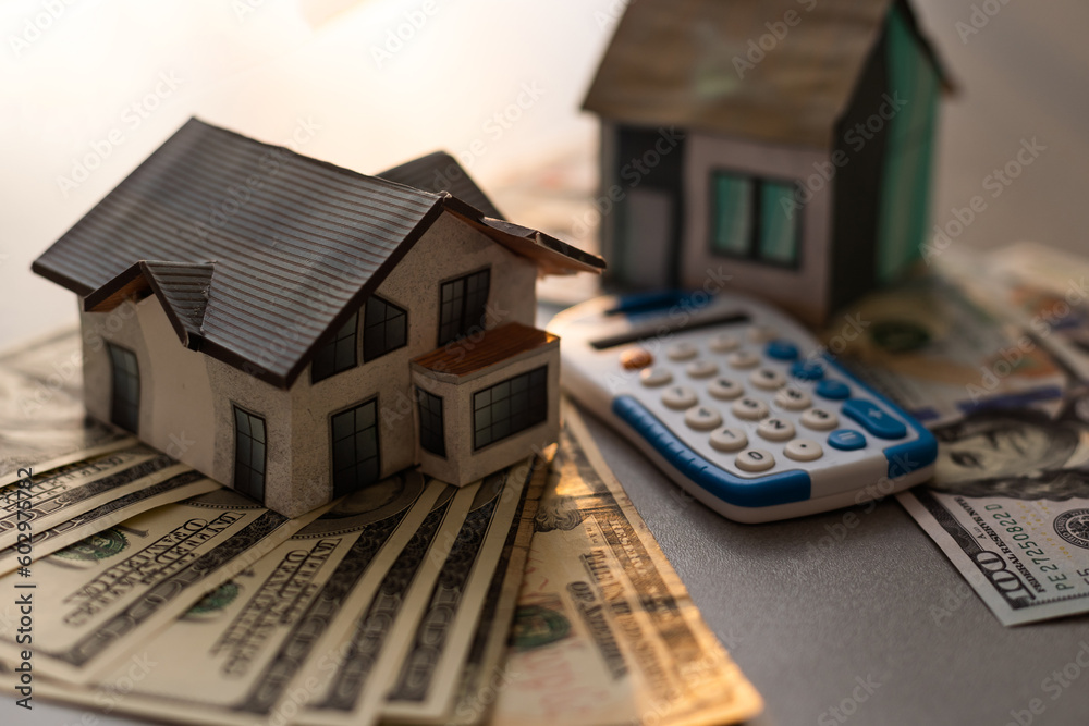 paper houses, money and calculator stands over a wooden background. paper houses, money and calculator stands over a wooden background.