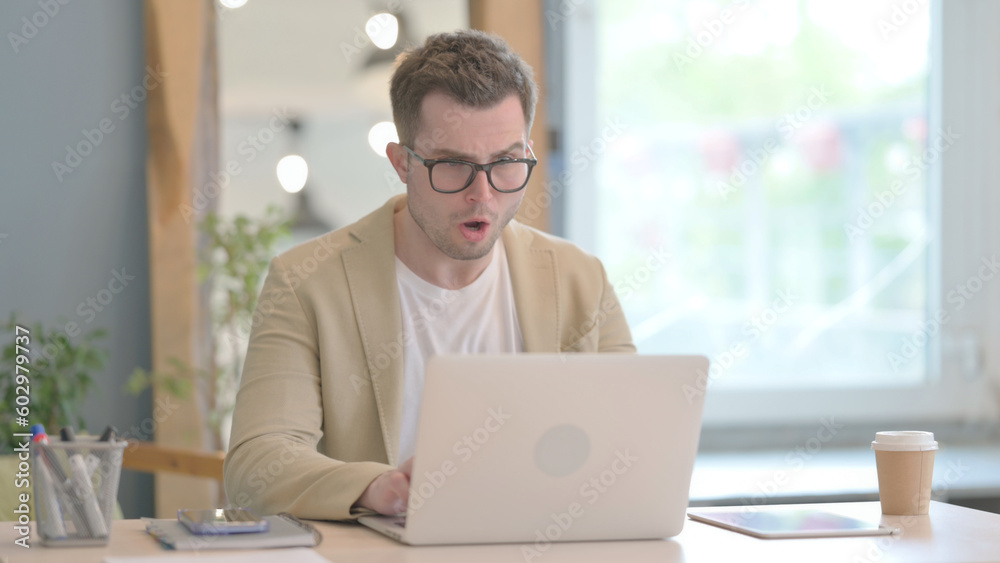 Young Businessman Shocked by Loss on Laptop Young Businessman Shocked by Loss on Laptop