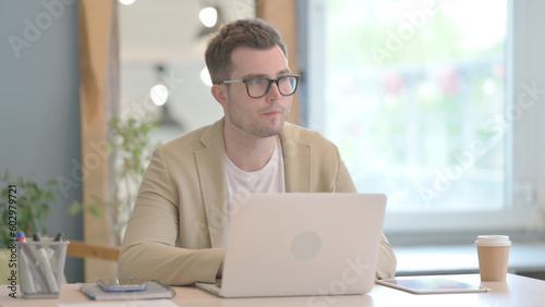 Young Businessman Thinking and Working on Laptop