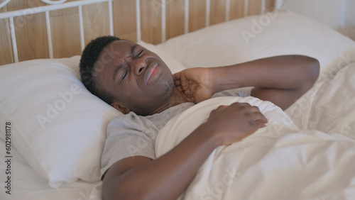 Tired Young African Man with neck Pain Sleeping in Bed