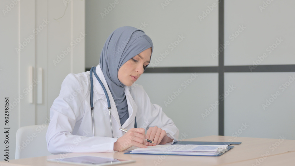 Muslim Female Doctor Working on Medical Report in Clinic Muslim Female Doctor Working on Medical Report in Clinic