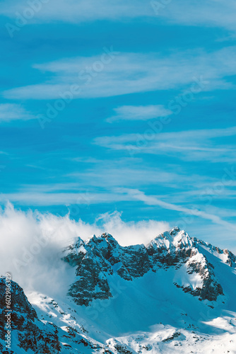 Clouds rolling over snowcapped mountain top in Julian Alps range during winter