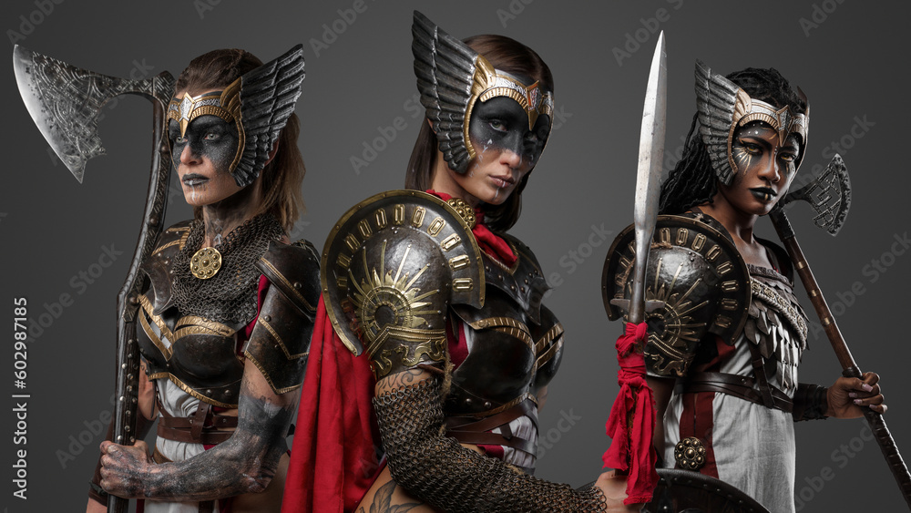 Shot of three amazons with armour and axes against gray background.