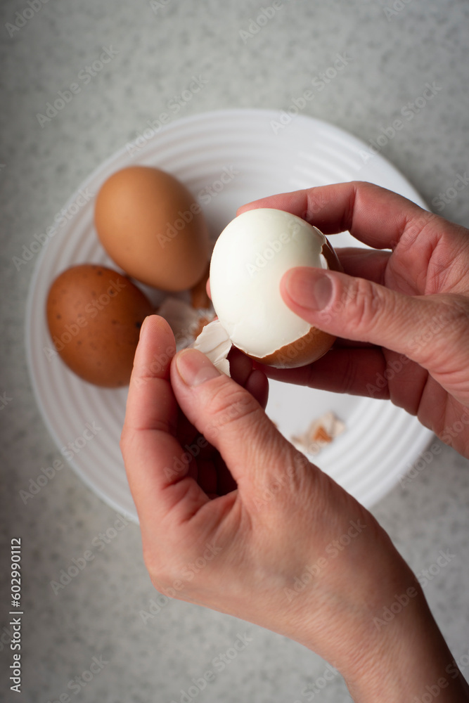 Caucasian female peeling hard boiled eggs closeup view from above