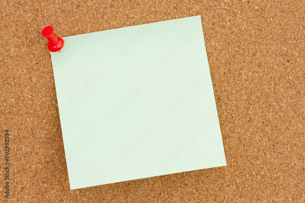 Blank green sticky note on bulletin board Blank green sticky note on bulletin board