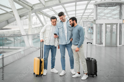 Three Tourists Men Using Smartphones Using Travel Application At Airport