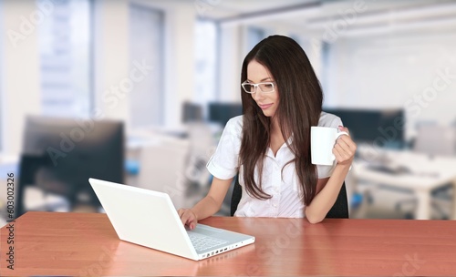 Young happy business woman working on laptop in office