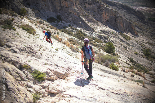 Sportsmen and women climb mountain through via ferrata in Villena, Spain. photo